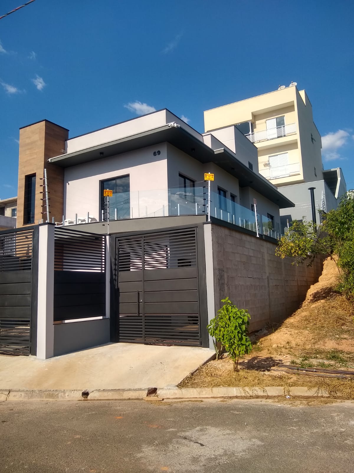 Casa moderna com portão de alumínio preto e guarda-corpo de vidro
