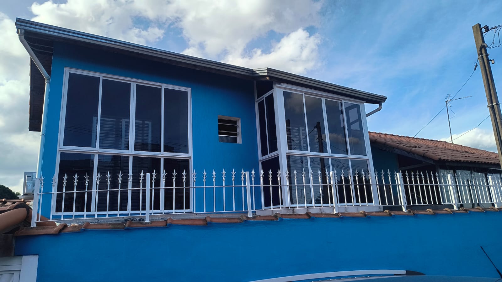 Fachada azul com janelas de alumínio branco sob medida